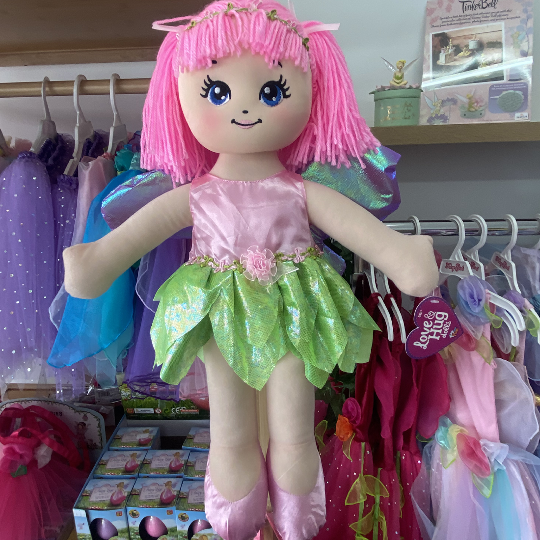 A colorful 18 inch Love & Hug butterfly pixie fairy doll with pink hair, wearing a green and pink outfit with a satin bodice and wings.
