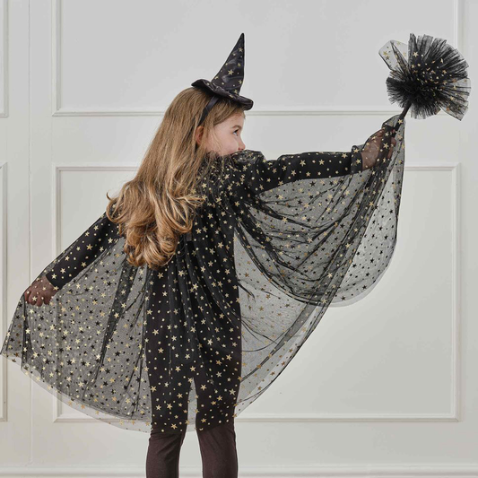 A child's witches black cape with gold stars , model is wearing the matching witches hat headband and holding the matching broom.
