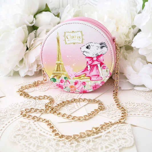 Small round pink purse with a mouse and Eiffel Tower design, placed on a white floral background.