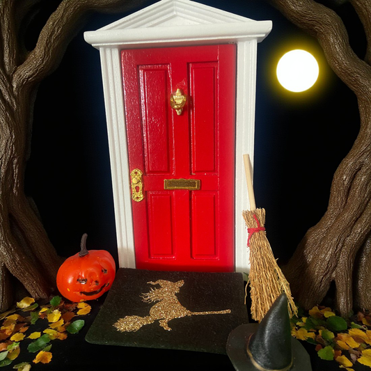 Red door with a broom, pumpkin, and witch's hat and a door mat with a witch flying on it