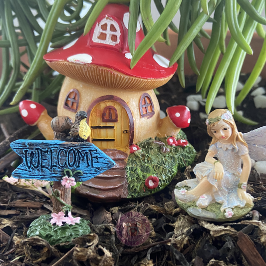 Miniature fairy house with a red roof, mushroom-shaped door, and decorative elements on a natural background.
