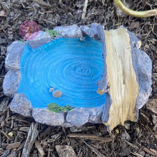 A miniature blue pond with a wooden bridge