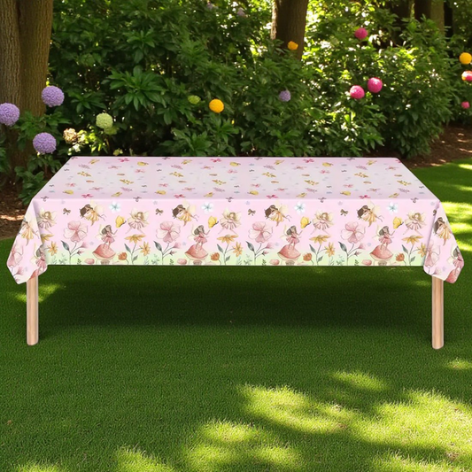 Table with a floral tablecloth outdoors on a grassy area with flowers in the background