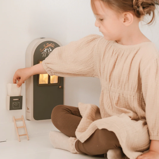 Child playing with a toy mailbox in a cozy indoor setting