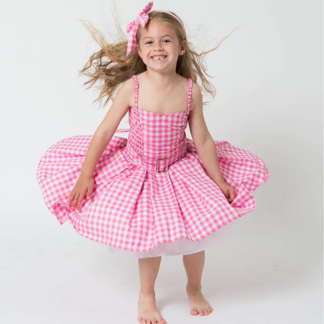 Young girl wearing a pink gingham dress on a white background