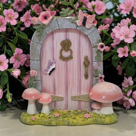 Pink fairy door with mushrooms and butterflies surrounded by pink flowers