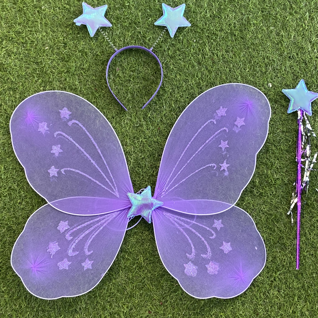 Purple fairy wings, headband, and wand on grass