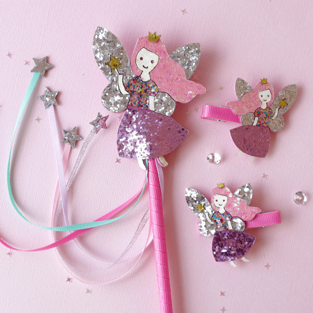 Fairy-themed hair accessories including a wand, headband, and clip on a pink background.