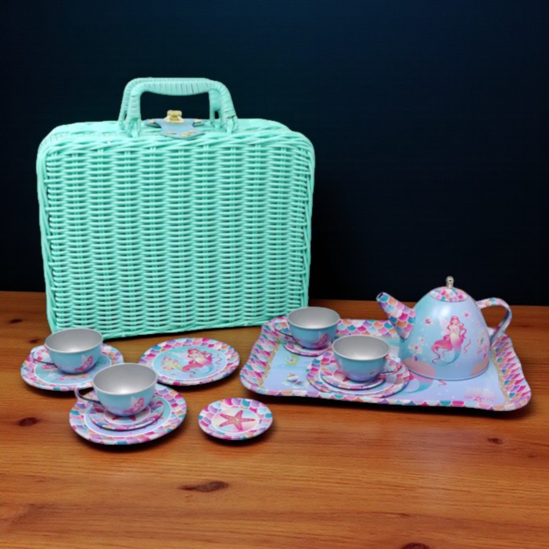 Children's tea set with a turquoise wicker basket on a wooden surface.