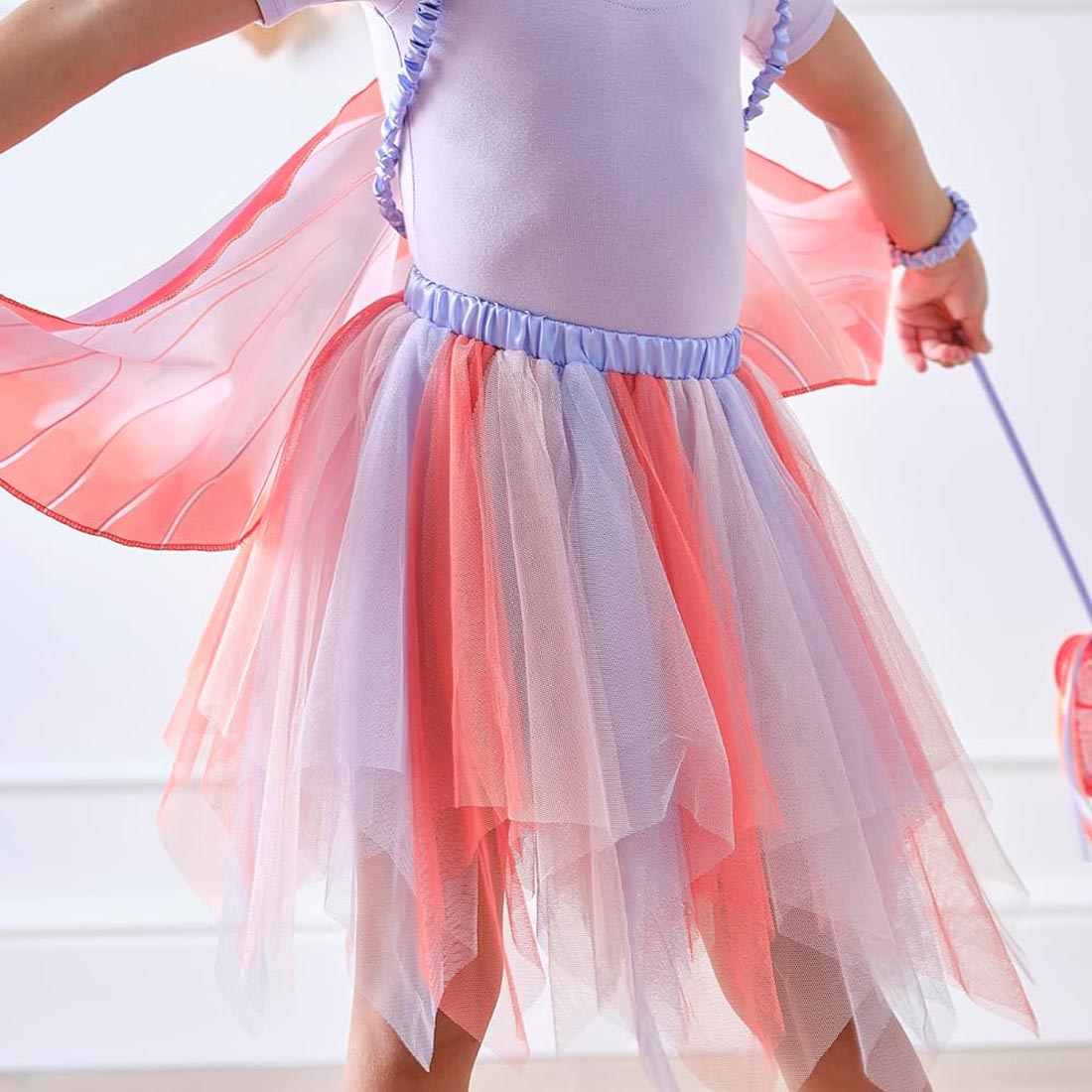 Person wearing a white top and pink tulle skirt with a blurred background
