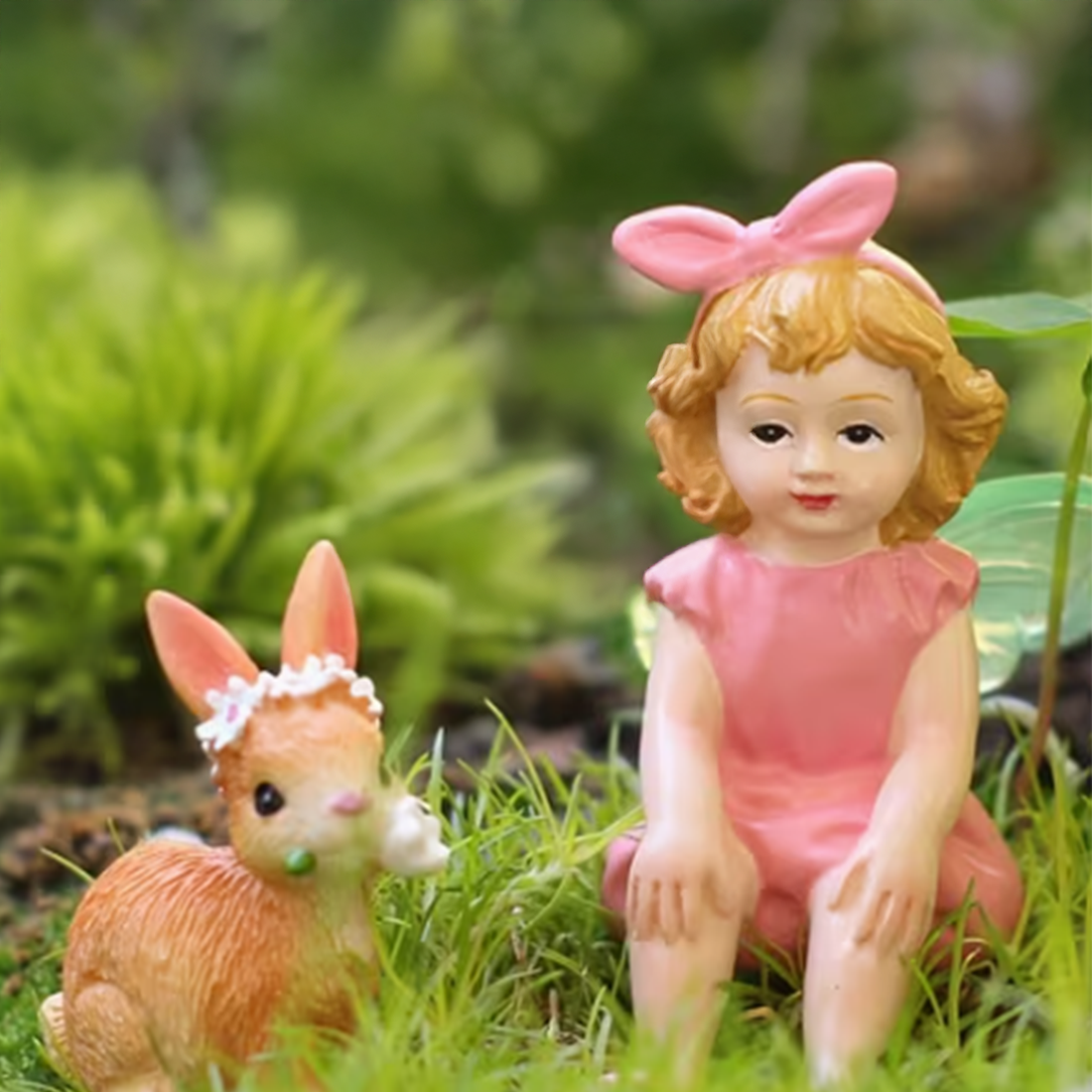 Small figurine of a girl with a pink bow and a deer-like creature in a grassy setting.