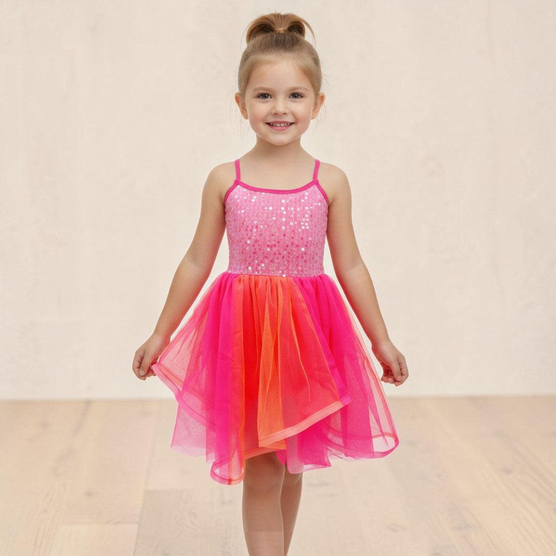 Young girl wearing a pink and orange dress with sequined top on a beige background