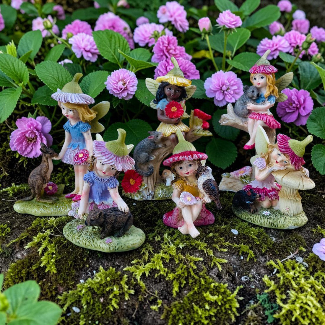 Set of fairy figurines with animals on a natural background with flowers and plants.