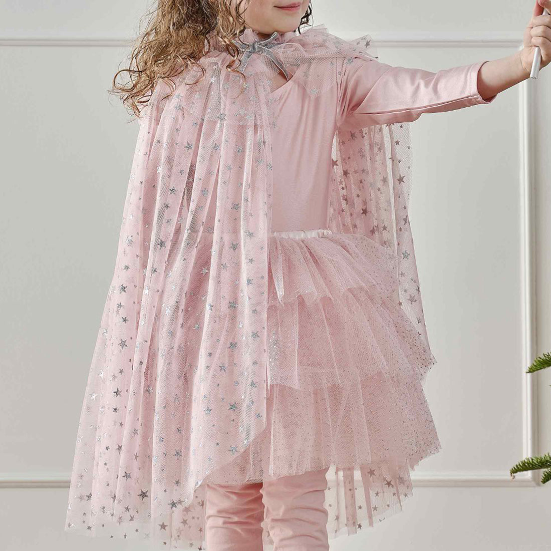 Child wearing a pink outfit with a sheer overlay against a white background